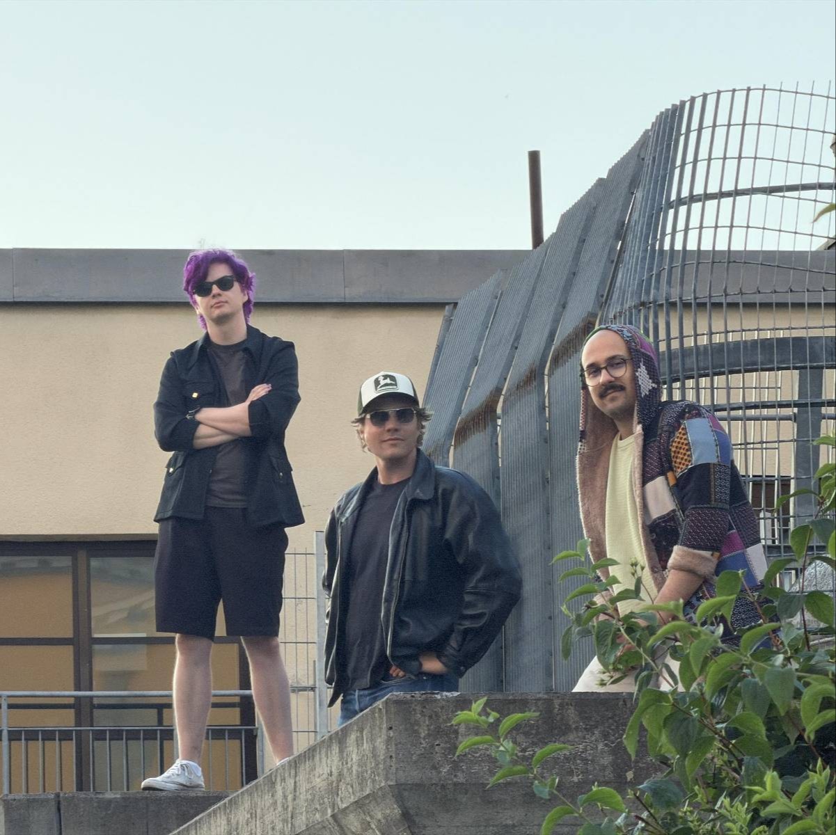 The three band members posing on concrete steps in front of a building